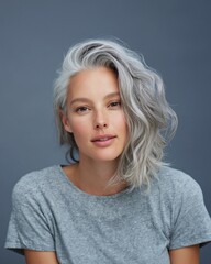 Naklejka premium Young woman with grey hair wearing a gray t-shirt poses against a neutral background, showcasing her natural beauty and relaxed expression in a close-up portrait