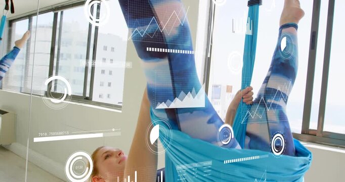 Yoga practitioner entering blue silk hammock and drawing knees inward, inverting body for fitness