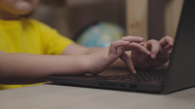 close-up children hands press keys keyboard. Slow motion. child studying lesson school at desk. digital computer learning kid at home. son boy send homework to online school. kid training on internet.