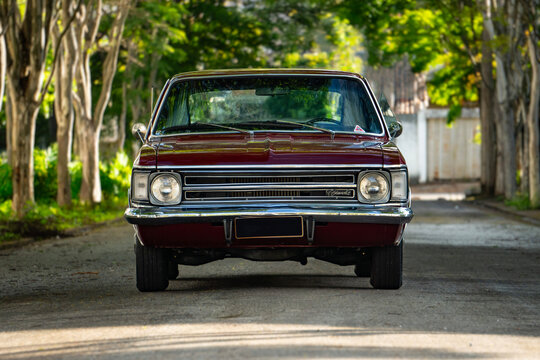 Dark red Chevrolet Opala front view centered, Classic vintage coupe parked on tree lined avenue
