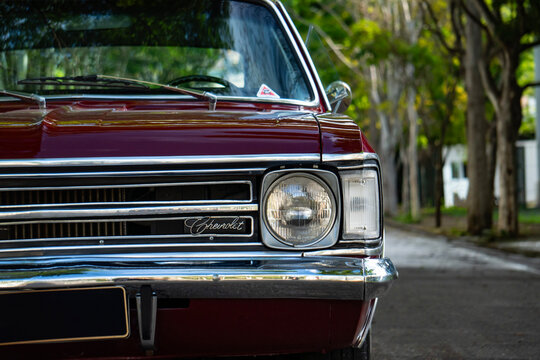 Dark red Chevrolet Opala front right headlight and grille, Classic retro car front end details outdoors