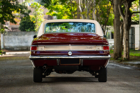 Burgundy Chevrolet Opala rear view centered, Classic vintage car on tree lined street
