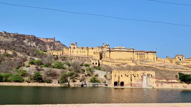 A bright daytime  showing the majestic Amer Fort complex built on the Aravalli hills, with yellow sandstone walls.