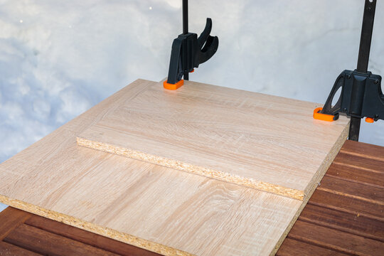 Chipboard boards are glued and held together with two clamps.
