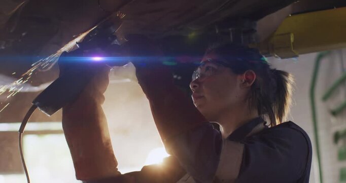 Animation of blue light moving over mid asian mechanic repairing car with grinding tool in garage