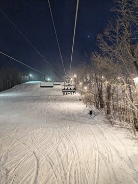 Night skiing in winter - chairlift and ski slopes for skiing and snowboarding  between trees on a frosty night with beautiful views in  mountains