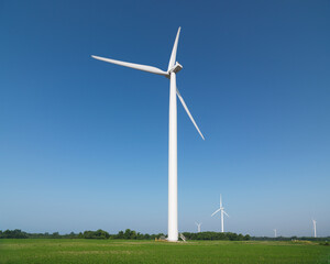 Fototapeta premium Wind Turbines in green summer field countryside scenery