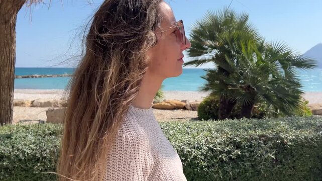 Push in suave hacia rostro de mujer caminando por paseo mar&iacute;timo