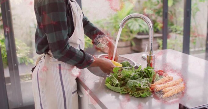 Woman preparing vegetables for home cooking, turning faucet and rinsing peppers under chrome spout