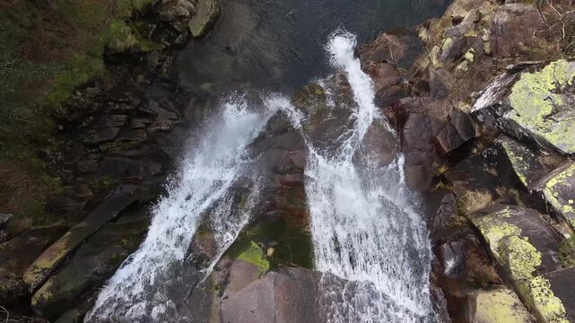 Water rushing down a multi-tiered rock formation into a calm pool in a natural landscape
