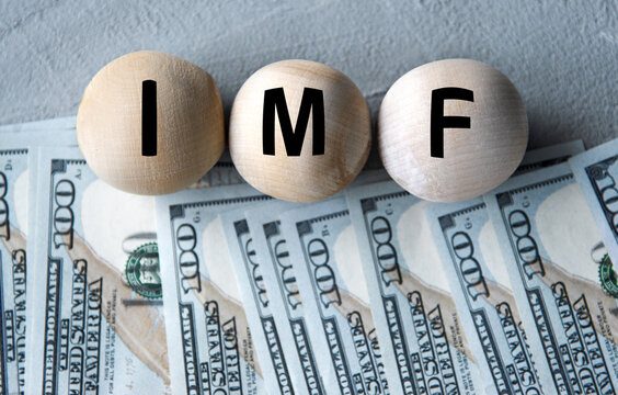 IMF - acronym on wooden balls on the background of banknotes