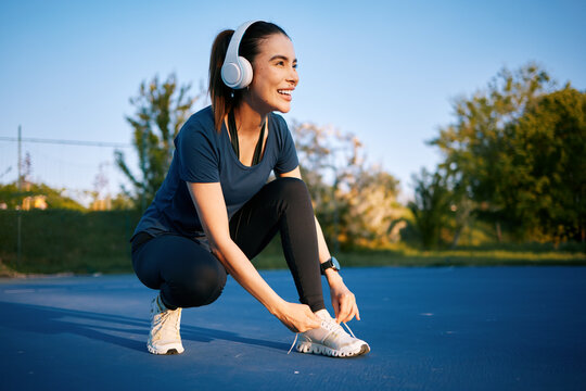 Woman lacing up running shoe preparing for jogging workout