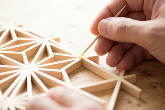 Craftsman applying wood glue with a toothpick to a delicate Japanese kumiko wooden pattern
