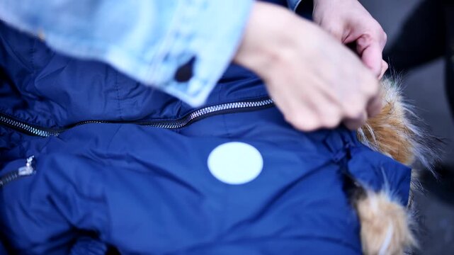 Adult hands adjusting straps on a blue winter snowsuit preparing for cold weather