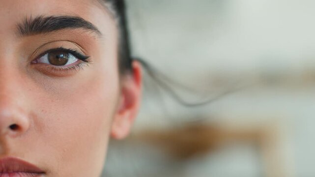 Close up half face Indian Muslim woman looking at camera home serious pensive expression eyesight vision health problem Arabian lady female girl considering laser correction indoors lifestyle headshot