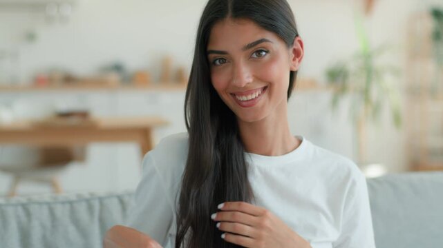 Happy smiling Indian Arabian woman brushing hair with comb at home indoors Muslim female carefree healthy girl beauty routine smooth shiny haircare eco shampoo mask conditioner cosmetic hairstyling