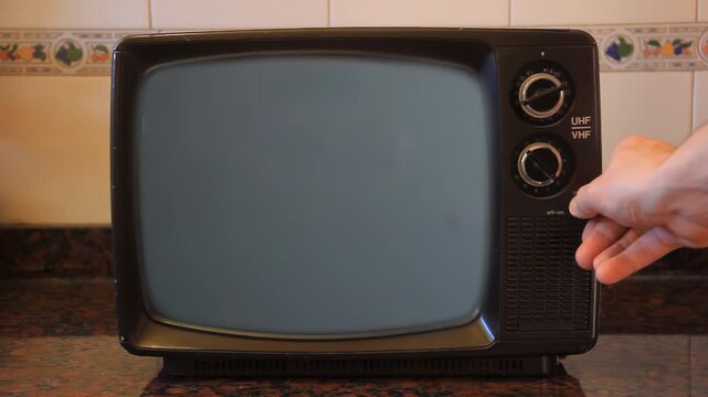 Hand Changing Channels on Retro Television in Kitchen