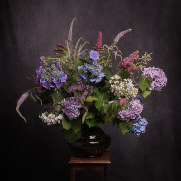 painterly classic studio arrangement with hydrangea and hortensia flowers in vase in blue and purple