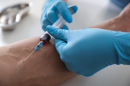 Nurse drawing man's blood sample in clinic, closeup
