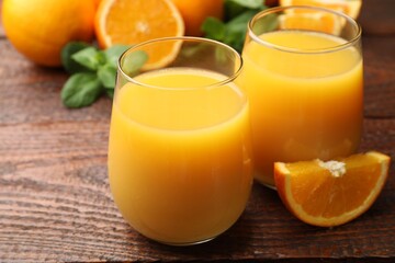 Citrus juice in glasses, fresh oranges and mint leaves on wooden table, closeup © New Africa