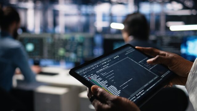 Close up of data center software developer using tablet to review code for automation scripts. Server hub IT specialist using device, monitoring error logs for debugging processes, camera A