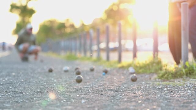 Petanque boules bouncing on gravel court at sunset