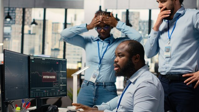 Teamworking traders in office work together to resolve security alert after hacker uses exploit to penetrate systems. Team of prop firm colleagues brainstorm how to protect from cyberattack