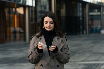 Obraz premium Woman treating bronchial asthma with inhaler for easier breathing on street.