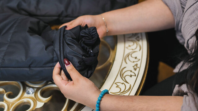 Woman examining material detail of a black nylon jacket sleeve