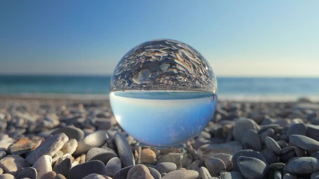 Crystal ball reflecting a person walking on a mediterranean beach