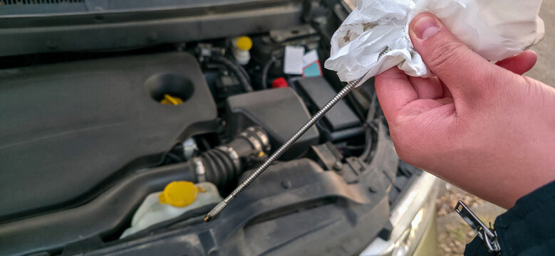 A man is checking the oil level in an internal combustion engine. Safety when going on the road. High-quality operation of the car engine