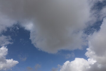 Obraz premium Beautiful blue sky with white fluffy cumulus clouds. Summer day background. High resolution nature texture suitable for wallpaper or design overlays