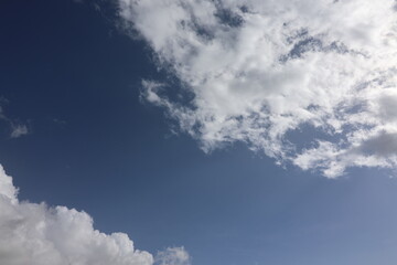 Obraz premium Beautiful blue sky with white fluffy cumulus clouds. Summer day background. High resolution nature texture suitable for wallpaper or design overlays