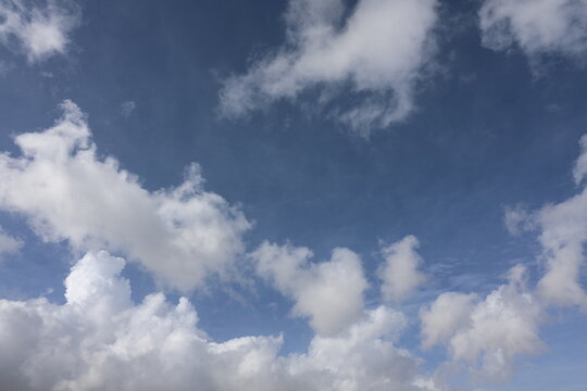 Beautiful blue sky with white fluffy cumulus clouds. Summer day background. High resolution nature texture suitable for wallpaper or design overlays