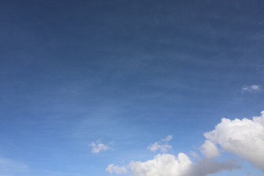 Beautiful blue sky with white fluffy cumulus clouds. Summer day background. High resolution nature texture suitable for wallpaper or design overlays