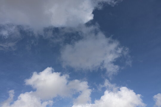 Beautiful blue sky with white fluffy cumulus clouds. Summer day background. High resolution nature texture suitable for wallpaper or design overlays