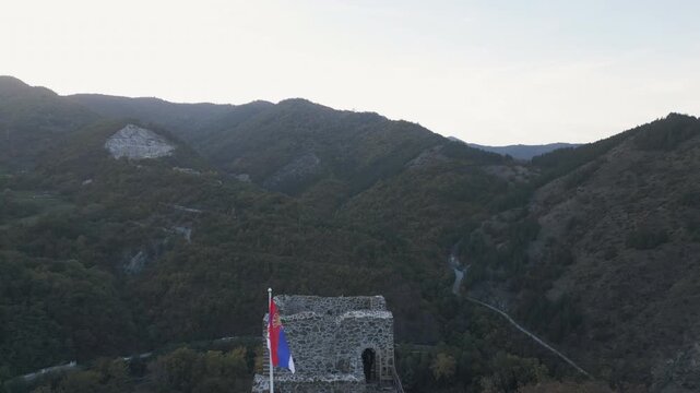 Drone pull away revealing Serbian flag waving on Maglic fortress in western Serbia.
