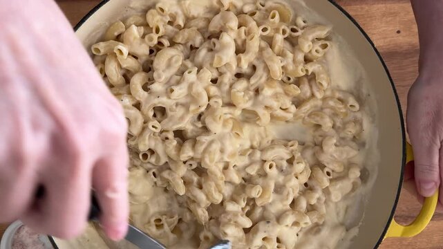 Stirring a Delicious Pan of Creamy Macaroni and Cheese Pasta Shot from Above