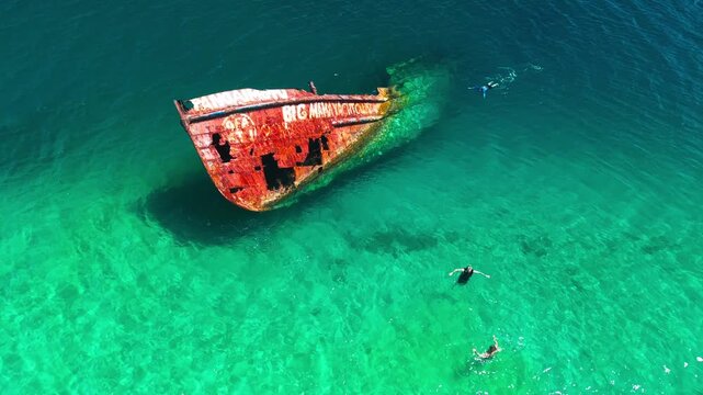 Aerial Drone View of Old Shipwreck Surrounded by Coral Reef in Blue Pacific Waters