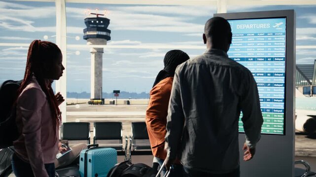 Diverse passengers panicking inside international airport terminal after all flights cancelled, shown in red on departures information board. Travelers appear angry by disrupted travel plans.