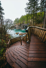 Obraz premium A wooden staircase descends along a rugged coastal cliff overlooking turquoise ocean water at Cape Flattery, Olympic National Park