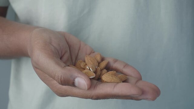 Close up of person hand picking up almonds from palm, healthy snack food, nutritious nuts in motion
