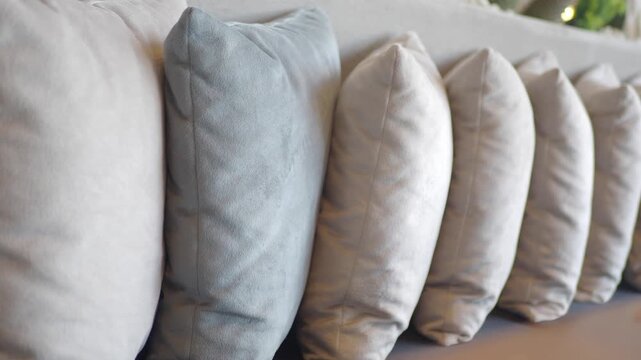 A row of pillows in varying shades of light gray and blue create an elegant and comfortable backdrop, captured in a slow motion video