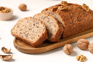 Naklejka premium Wooden plate with delicious walnut loaf cake on light background
