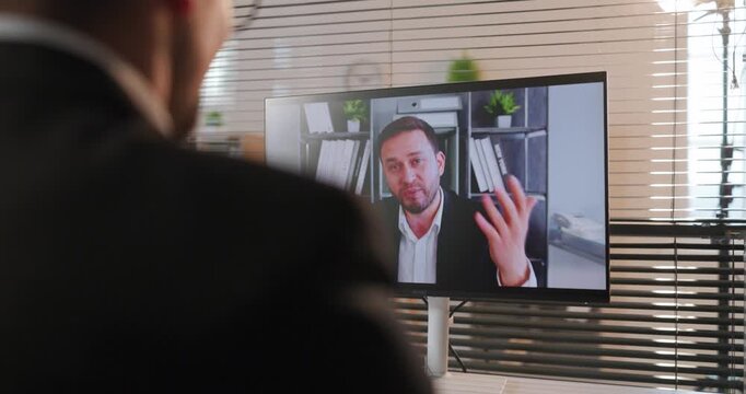Business office man video call meeting online. Executive on monitor gestures as coworker listens, collaboration, chat, consulting and interview context. Concept of remote work communication.