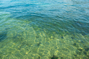 Obraz premium Clear turquoise water, sunlight reflecting, symbolizing natural beauty and serene aquatic scene, bottom through transparent water, blue background, natural resources planet