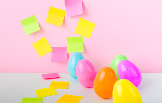 Colorful easter eggs with falling sticky notes on pastel background creative spring holiday planning concept with copy space.