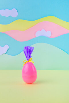 Cute pink easter egg with bow and wrapping on soft pastel background with clouds spring holiday minimal banner with copy space.