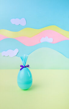 Modern minimal easter background with single wrapped egg in pastel colors with clouds and large copy space for design. Egg blue.