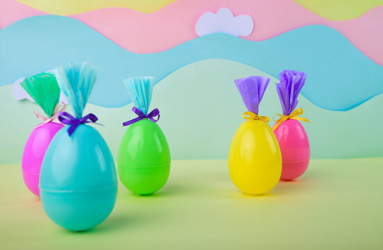 Cute colorful easter eggs with bows and wrapping on soft pastel background with clouds spring celebration holiday concept for kids.